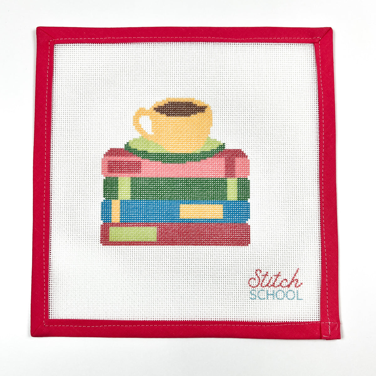 Just One More Chapter needlepoint canvas with a yellow coffee cup and green saucer on colorful stacked books, shown with red binding.