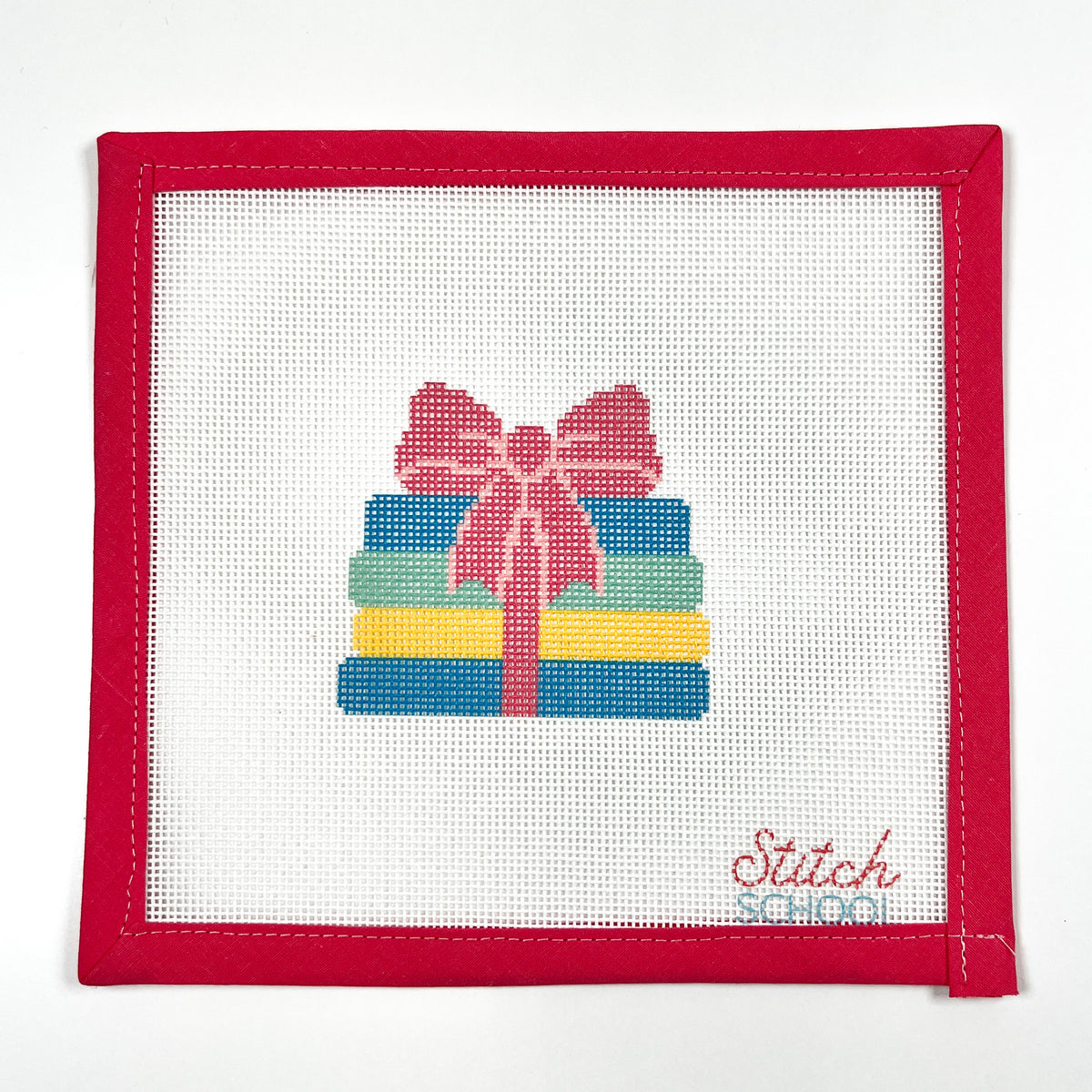 Books with a Bow needlepoint canvas with colorful stacked books tied with a pink bow, shown with red binding.